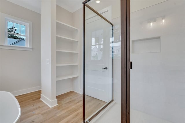 bathroom with wood-type flooring and shower with separate bathtub