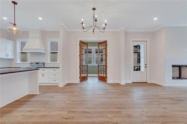 kitchen featuring a fireplace, decorative light fixtures, light hardwood / wood-style floors, and custom exhaust hood