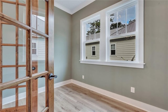 unfurnished room featuring french doors, light wood-type flooring, and ornamental molding