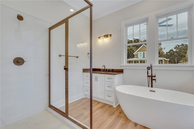 bathroom with hardwood / wood-style floors, vanity, and plus walk in shower