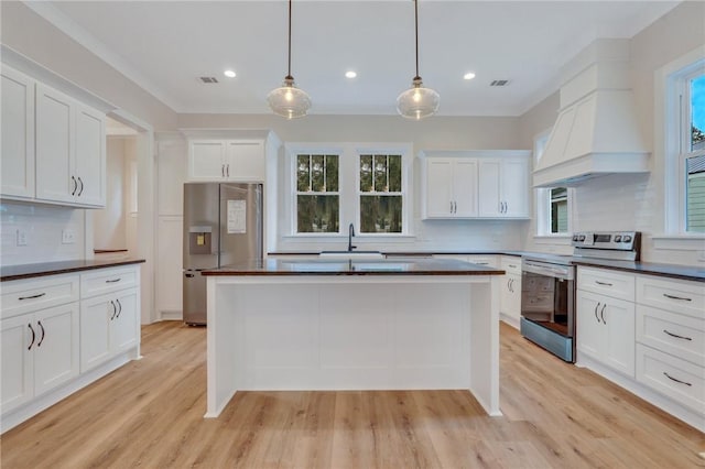 kitchen with pendant lighting, white cabinets, light wood-type flooring, and stainless steel appliances