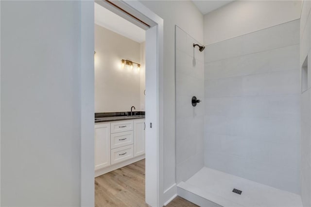 bathroom with vanity, wood-type flooring, and tiled shower