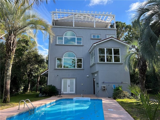 rear view of property featuring french doors, a balcony, and a patio