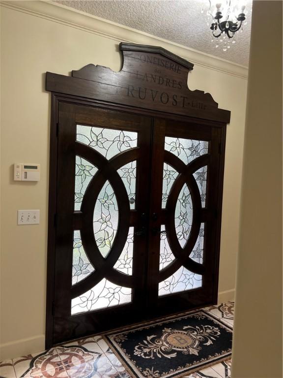 entryway with crown molding, an inviting chandelier, and a textured ceiling