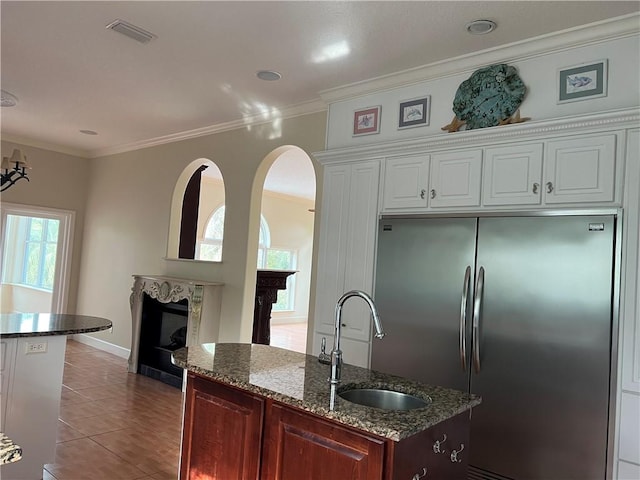 kitchen featuring sink, ornamental molding, stainless steel fridge, a premium fireplace, and white cabinets