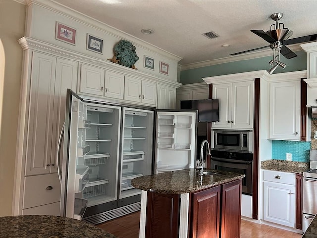 kitchen with sink, appliances with stainless steel finishes, ornamental molding, an island with sink, and ceiling fan