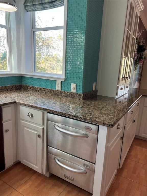 kitchen with white cabinetry, dark stone countertops, and light wood-type flooring