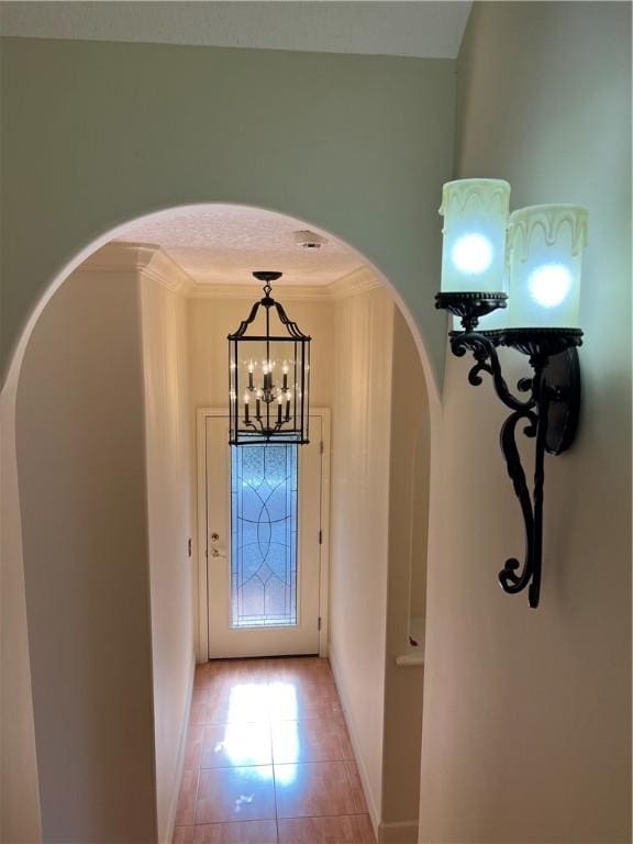 doorway to outside with crown molding and light tile patterned flooring