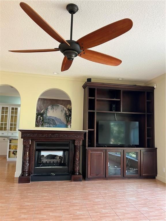 unfurnished living room featuring ceiling fan, a multi sided fireplace, a textured ceiling, and light tile patterned floors