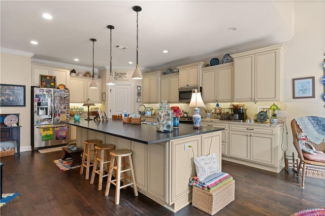 kitchen featuring a kitchen island with sink, cream cabinets, and stainless steel appliances