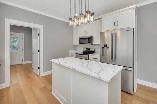 kitchen featuring white cabinets, light wood-type flooring, appliances with stainless steel finishes, decorative light fixtures, and a kitchen island