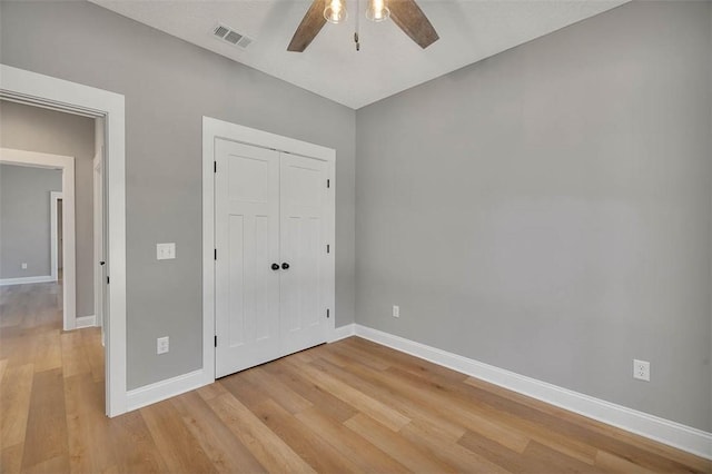 unfurnished bedroom featuring ceiling fan, light wood-type flooring, and a closet