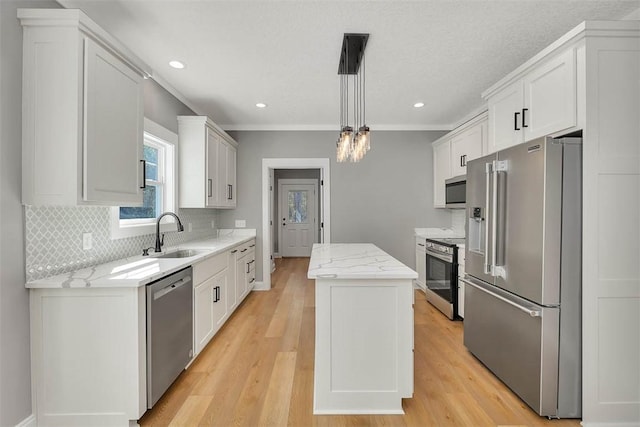 kitchen with pendant lighting, a center island, white cabinets, sink, and stainless steel appliances