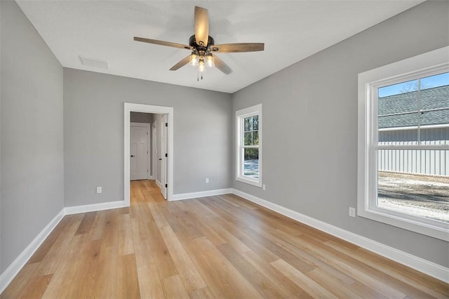 empty room with plenty of natural light, ceiling fan, and light wood-type flooring