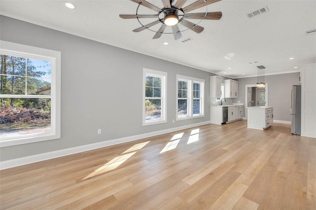 unfurnished living room featuring light hardwood / wood-style floors, plenty of natural light, crown molding, and ceiling fan