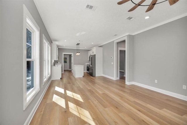 unfurnished living room featuring ceiling fan, crown molding, sink, and light hardwood / wood-style flooring