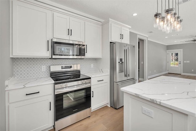 kitchen with white cabinets, decorative light fixtures, light wood-type flooring, and appliances with stainless steel finishes