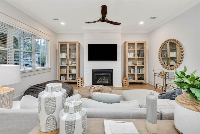 living area with a large fireplace, ceiling fan, wood finished floors, ornamental molding, and recessed lighting