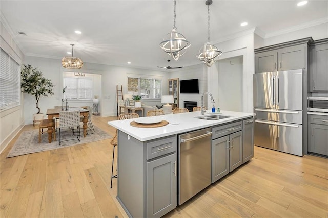 kitchen with stainless steel appliances, a sink, a chandelier, gray cabinetry, and light countertops