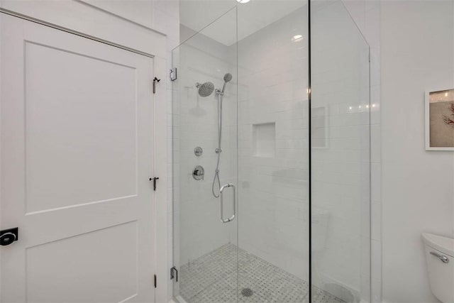 bathroom featuring toilet and a shower stall