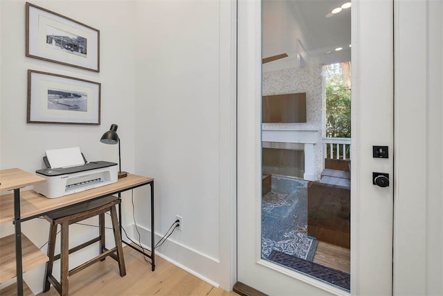 doorway to outside with wood finished floors, baseboards, an office area, and a fireplace