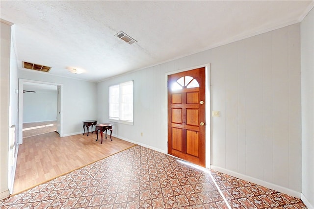 entryway with ornamental molding, hardwood / wood-style floors, and a textured ceiling