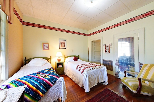 bedroom featuring dark hardwood / wood-style floors, heating unit, and a drop ceiling