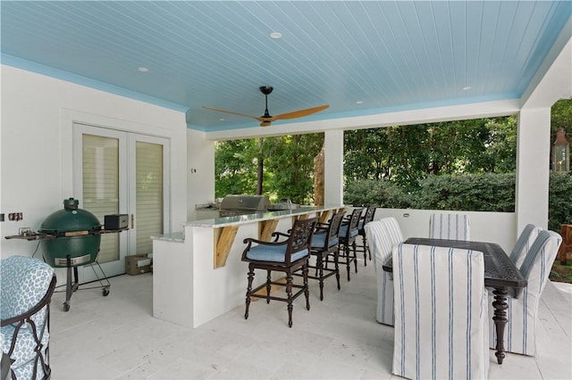 view of patio featuring ceiling fan, area for grilling, and a bar