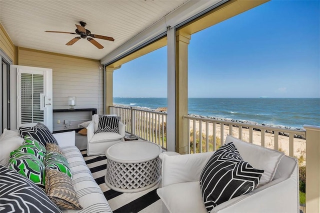 balcony featuring ceiling fan, a water view, and a view of the beach