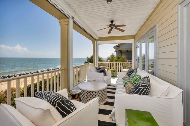 balcony featuring ceiling fan, a water view, and a beach view