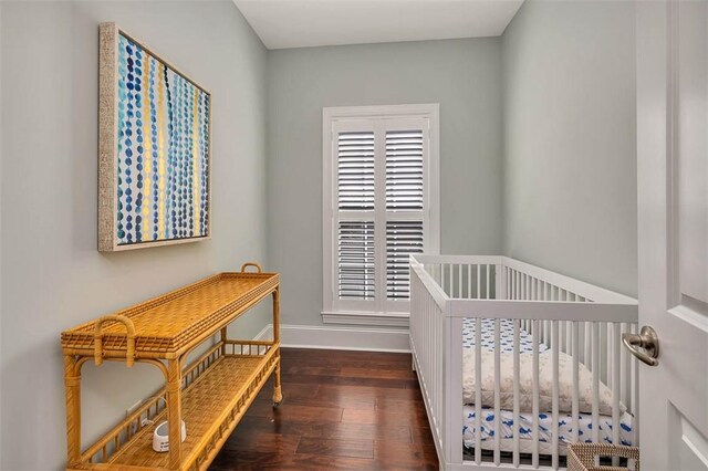 bedroom featuring a crib and dark wood-type flooring
