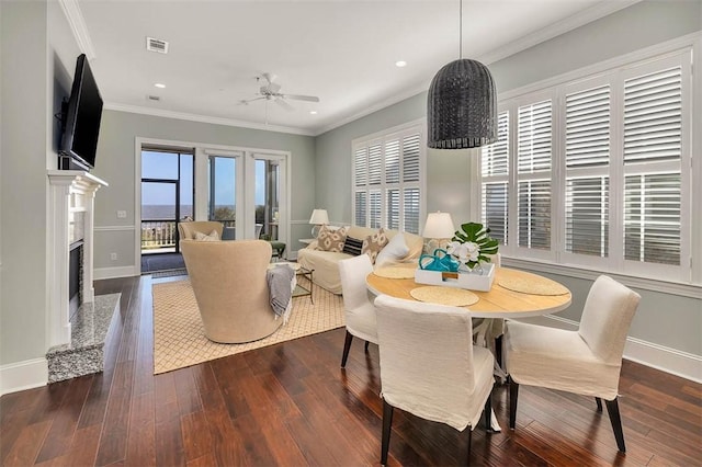 dining area featuring ceiling fan, dark hardwood / wood-style flooring, a high end fireplace, and crown molding