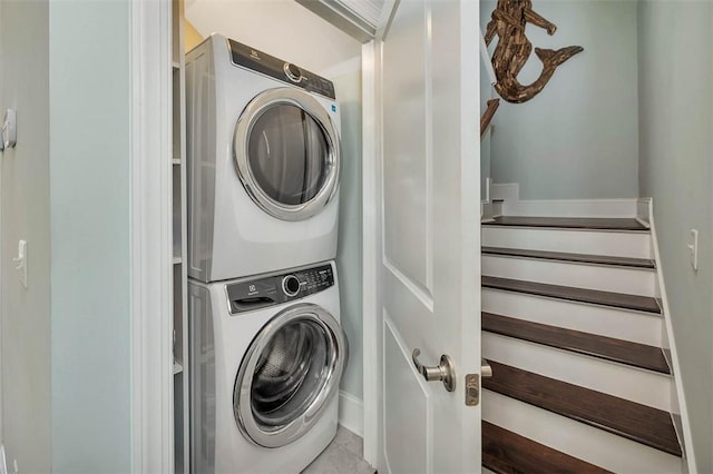 laundry room with tile patterned flooring and stacked washer / dryer