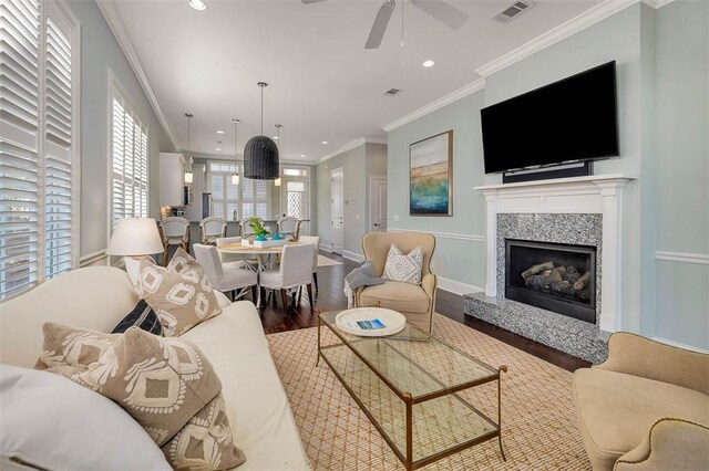 living room featuring a fireplace, wood-type flooring, ceiling fan, and ornamental molding