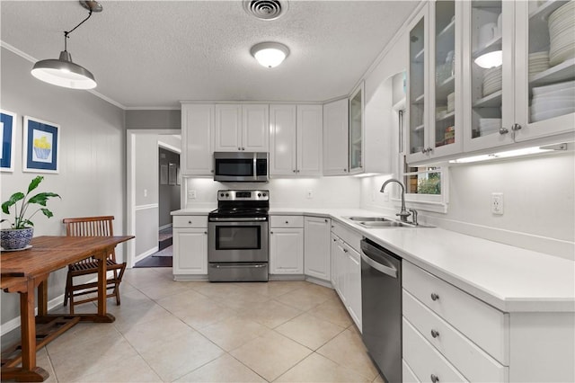 kitchen with appliances with stainless steel finishes, white cabinetry, sink, hanging light fixtures, and light tile patterned floors