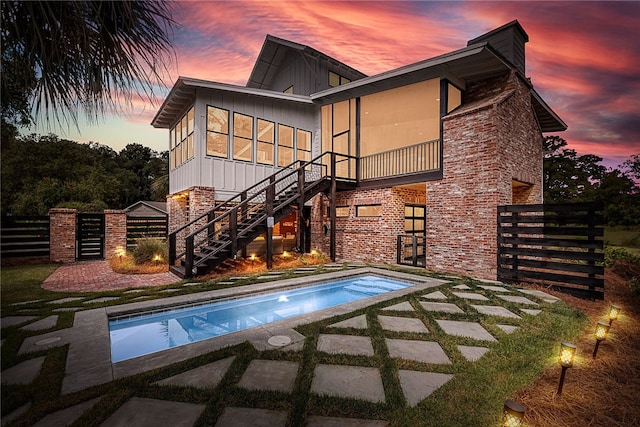 10 Fern Ln, Saint Simons Island, GA 31522 - back of property at dusk with board and batten siding, stairs, a chimney, and a patio area