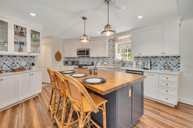 19 Wimbledon Ct, Saint Simons Island, GA 31522 - kitchen with appliances with stainless steel finishes, tasteful backsplash, light wood-style floors, white cabinets, and recessed lighting