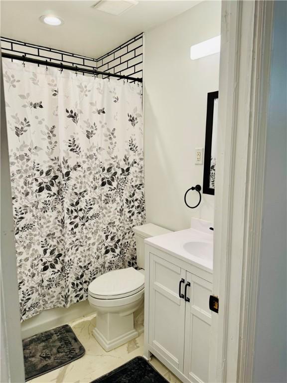 bathroom featuring a shower with shower curtain, vanity, and toilet