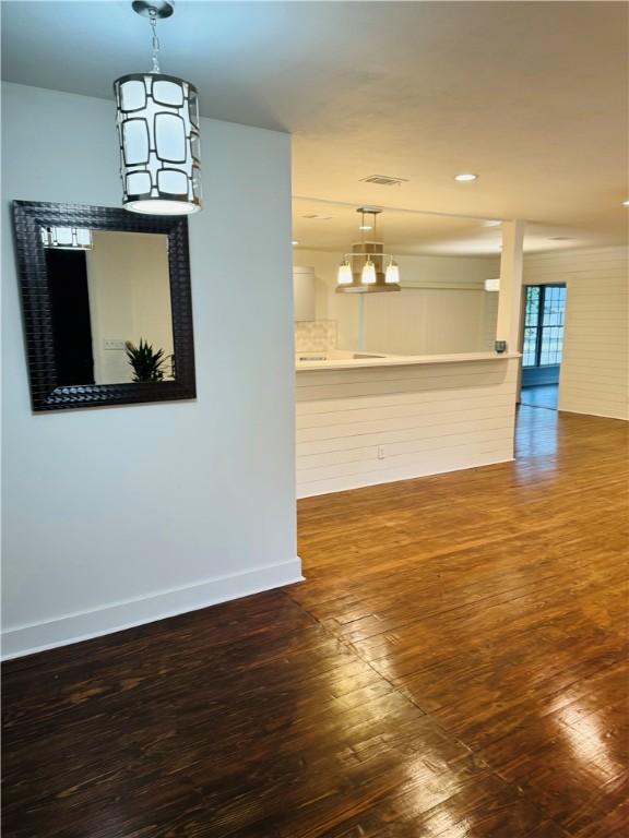 unfurnished dining area featuring a notable chandelier and dark hardwood / wood-style flooring