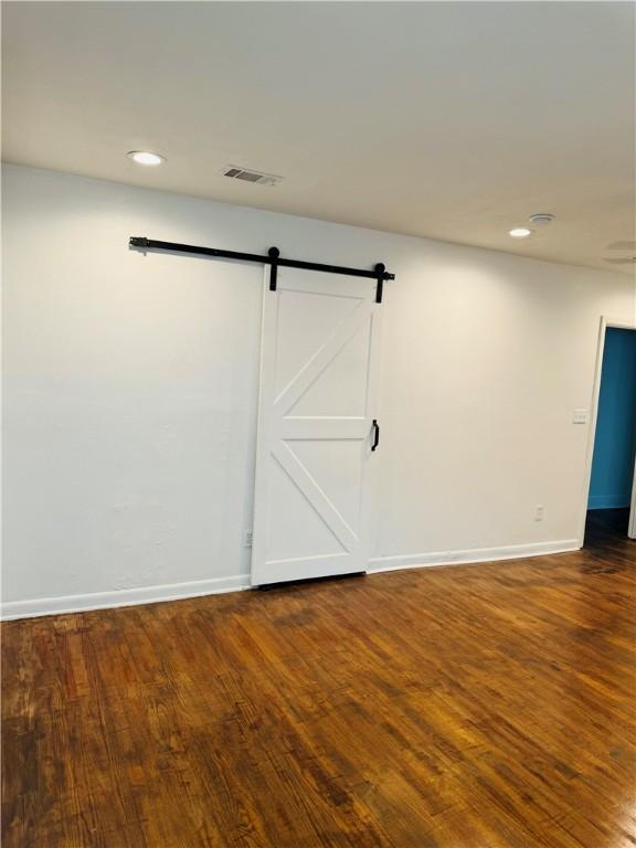 unfurnished room with a barn door and dark hardwood / wood-style flooring