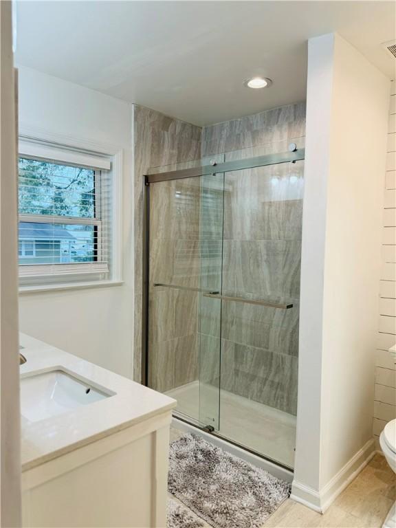 bathroom with tile patterned flooring, vanity, toilet, and an enclosed shower