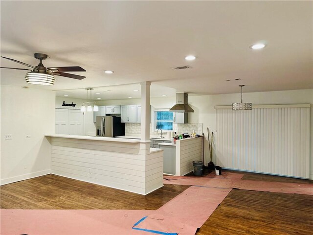 kitchen featuring island exhaust hood, stainless steel fridge, backsplash, white cabinets, and hardwood / wood-style floors