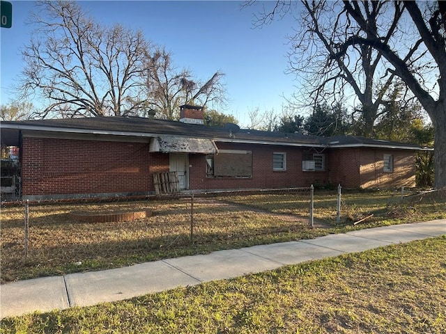 view of front facade featuring a fenced front yard, brick siding, and a chimney