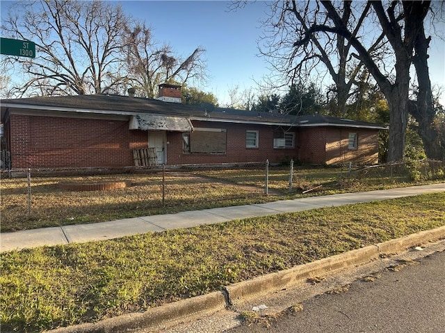 view of front of home with brick siding, a chimney, and a fenced front yard