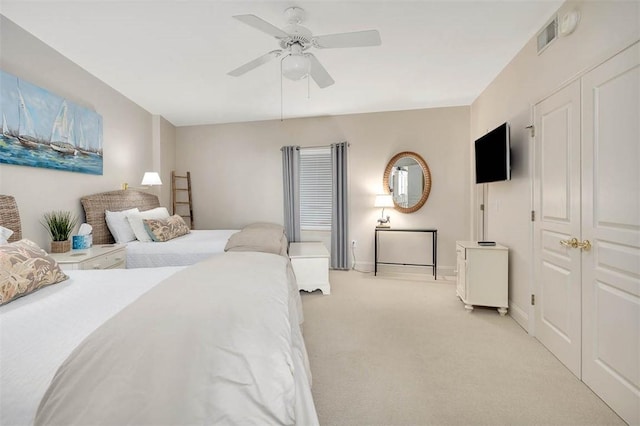 bedroom with ceiling fan, light colored carpet, and a closet