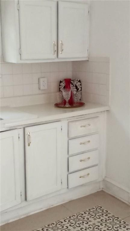 605 Walker St, Waycross, GA 31503 - kitchen featuring decorative backsplash, light countertops, white cabinets, and light tile patterned floors