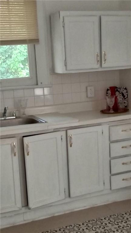 605 Walker St, Waycross, GA 31503 - kitchen featuring decorative backsplash, light countertops, and white cabinetry