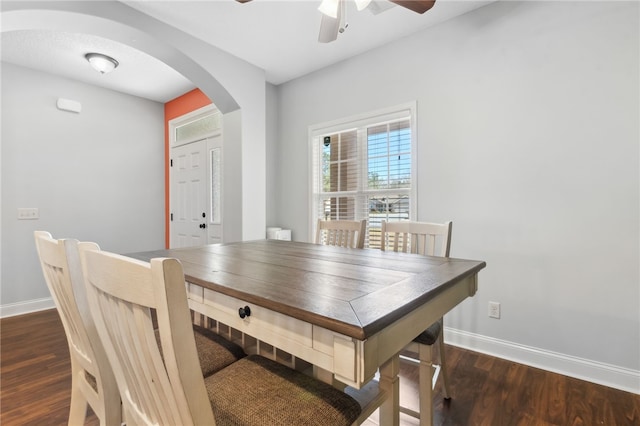 dining space featuring a ceiling fan, arched walkways, baseboards, and wood finished floors