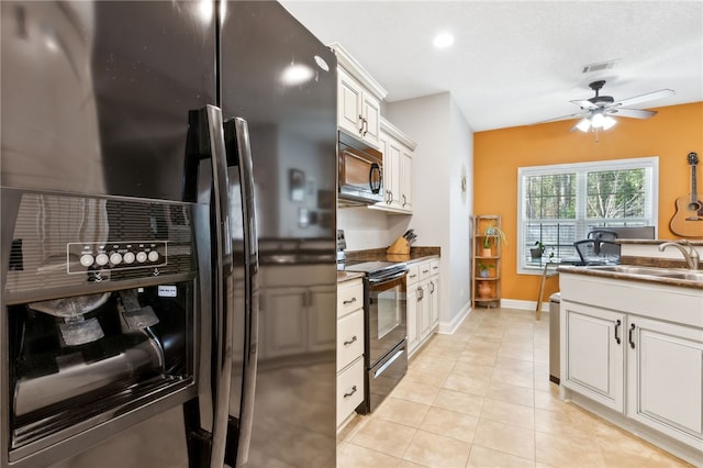 kitchen with light tile patterned floors, visible vents, white cabinets, a sink, and black appliances