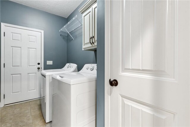 laundry area with cabinet space, light tile patterned flooring, a textured ceiling, and independent washer and dryer